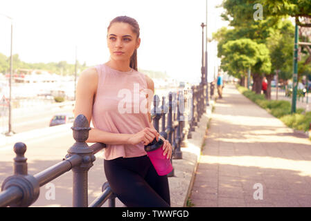 Schuss der jungen Frau mit einem Shaker in der Hand, und entspannen Sie nach dem Ausführen der Stadt. Stockfoto