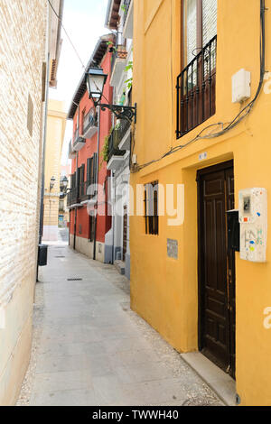 Bunte Wohnstraße in Granada, Spanien; ein Erdgeschoss Blick auf eine schmale leere Straße mit zwei- und dreistöckigen Apartment Gebäuden gesäumt. Stockfoto