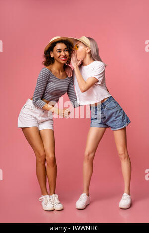 Junge Mädchen Tratschen auf rosa Hintergrund Stockfoto