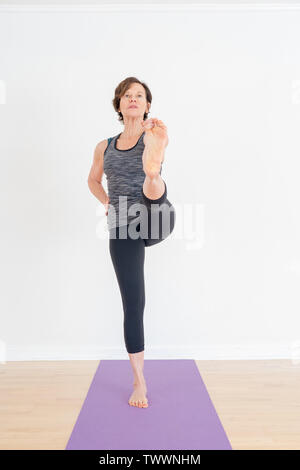 Eine 70 Jahre alte Yoga Lehrer in ihrem Atelier ist die verlängerte Hand-zu-Big-Toe darstellen Stockfoto