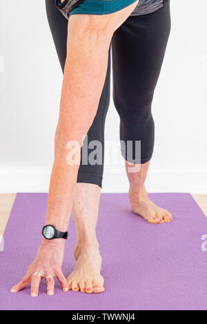 Eine 70 Jahre alte Yoga Lehrer in ihrem Studio Utthita parsvakonasana wie die erweiterte Seiten Winkel darstellen, aka Trikonasana Stockfoto