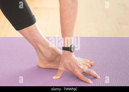 Detail eines 70 Jahre alten Yoga Lehrer in ihrem Studio Utthita parsvakonasana wie die erweiterte Seiten Winkel darstellen, aka Trikonasana Stockfoto