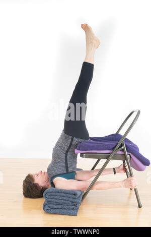 Salamba Sarvangasana, Shoulderstand mit Decke und Stuhl für die Unterstützung von einem 70 Jahre alten weiblichen Yoga-lehrer getan. Von der Seite gesehen. Stockfoto