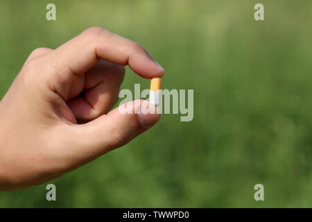 Pille in männlicher Hand auf verschwommenes grün Natur Hintergrund, Mann mit Medikation in der Kapsel hautnah. Konzept der Apotheke, Behandlung, Vitamine, Gesundheit Stockfoto