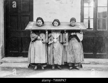Ein Ende des 19. oder Anfang des 20. Jahrhunderts vintage schwarz-weiß Foto zeigt drei chinesische Frauen in einem Cangue, ein Gerät für die öffentliche Demütigung verwendet oder manchmal in Teilen Ost Asien kann Folter gesperrt. Stockfoto