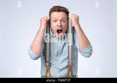 Gesicht der jungen europäischen Mann im blauen Hemd und Hosenträgern Schockiert Stockfoto
