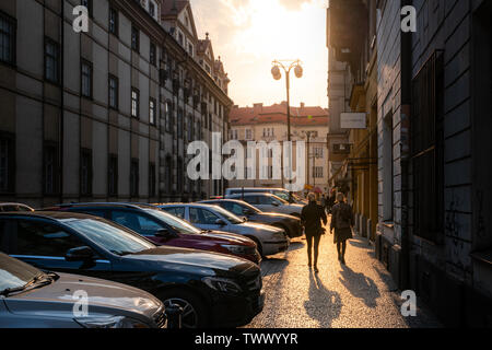 Prag, tschechische Republik - 10 April 2019: Eine schöne Aufnahme einer der Prager traditionellen gepflasterten Straßen bei Sonnenuntergang mit Touristen im Vordergrund. Stockfoto