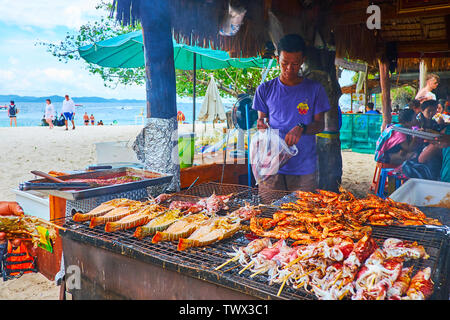 PHUKET, Thailand - Mai 1, 2019: Der junge Koch bereitet gegrillte Garnelen, Kalmaren und Hummer im Beach Cafe von Khai Nok Insel, am 1. Mai auf Phuket Stockfoto