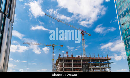 Skyscraper Bau. Zwei Turmdrehkrane. Und blauer Himmel. Skyline von Arbeitshöhe hoist Geräte. Truss Jib. Konkrete Rahmen. Hohes Gebäude. Stockfoto