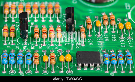 Farbige elektronische Komponenten. Widerstände, Transistoren, Kondensatoren, integrierten Schaltung auf der Platine. Standard Farbe Code. Grün Kupfer board Detail. E-Müll. Stockfoto