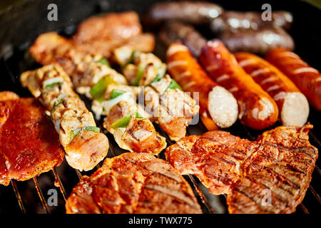 Verschiedene Arten von saftigen Fleisch auf heißen Kohlen auf Grill im Garten Stockfoto
