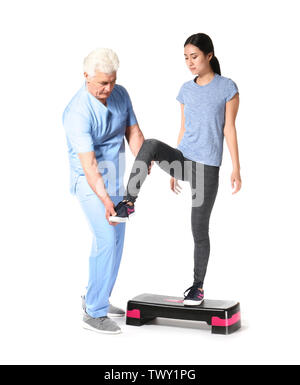 Reifen Physiotherapeuten arbeiten mit jungen asiatischen Frau auf weißem Hintergrund Stockfoto