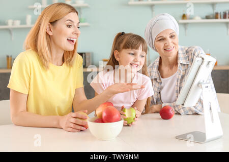 Reife Frau nach Chemotherapie mit ihrer Familie und Tablet-PC in der Küche zu Hause. Stockfoto