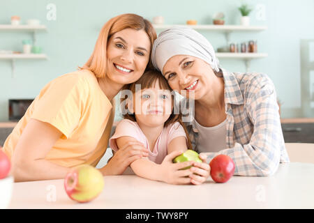 Reife Frau nach der Chemotherapie, die mit ihrer Familie in der Küche zu Hause. Stockfoto