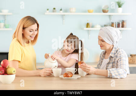 Reife Frau nach der Chemotherapie, die mit ihrer Familie in der Küche zu Hause. Stockfoto