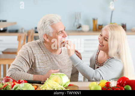 Reife Frau ihrem Ehemann Fütterung in der Küche Stockfoto