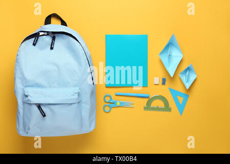 Rucksack mit Schulmaterial auf farbigen Hintergrund Stockfoto