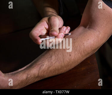 Man injiziert Schwarz tar Heroin in seinem Arm. Stockfoto