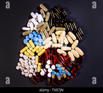 Ein bunter Haufen von Pillen sitzt auf einem Schwarzen Tisch. Stockfoto