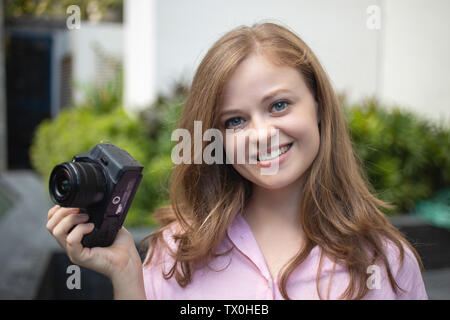 Porträt der jungen kaukasischen Frau photgrapher Holding eine Digitalkamera, lächelnd Stockfoto