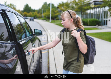 Jugendmädchen abgeholt werden von der Schule durch die Eltern. Stockfoto