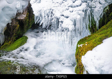 Ein kleiner Wasserfall auf einem Strom in der landschaftlich reizvollen Gegend im Tianshan Tianchi, Xinjiang im Winter ist mit Eiszapfen abgedeckt. Stockfoto