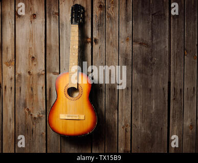 Die Gitarre hängt am alten hölzernen Wand Stockfoto