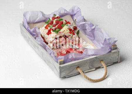 Holz- Fach mit Halbpension köstliche Baiser Kuchen mit Früchten auf einem weißen Hintergrund gegessen Stockfoto