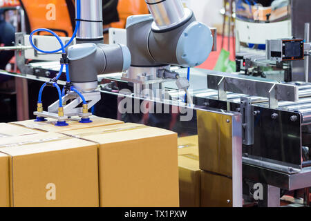 Der Roboterarm transfers Karton zu Fließband; close up Stockfoto