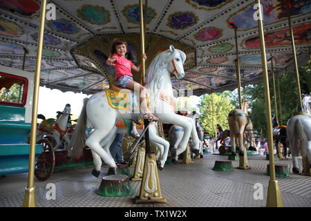 Das kleine Mädchen Fahrgeschäfte des Parks auf dem Karussell Stockfoto