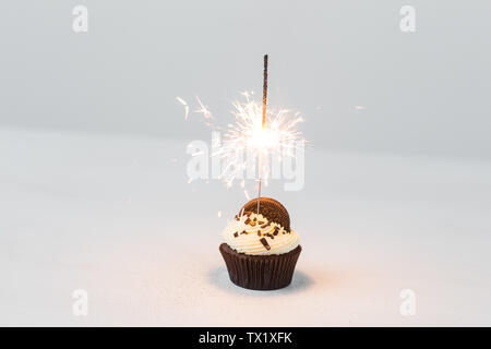 Essen, Party und Urlaub Konzept - Geburtstag Cupcake mit Wunderkerzen auf weißem Hintergrund Stockfoto