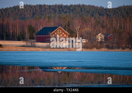 Bauernhof auf der östlichen Seite des Sees Saebyvannet in Våler Kommune, Østfold, Norwegen. Der See ist ein Teil des Wassers, das System namens Morsavassdraget. April, 2011. Stockfoto