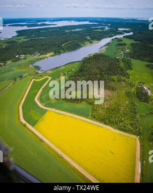 Luftaufnahme über einen Teil des Sees Vansjø und landwirtschaftliche Felder in Østfold, Norwegen, Skandinavien. Etwas oberhalb des Zentrums befindet sich der Fjord Grepperødfjorden, und dahinter befindet sich das offene Wassergebiet Storefjorden. Im Vordergrund steht ein Senfraps-Feld. Vansjø ist der größte See in Østfold. Der See Vansjø und seine umliegenden Seen und Flüsse sind Teil des Wassersystems namens Morsavassdraget. Der Blick geht Richtung Südosten. Juni 2006. Stockfoto