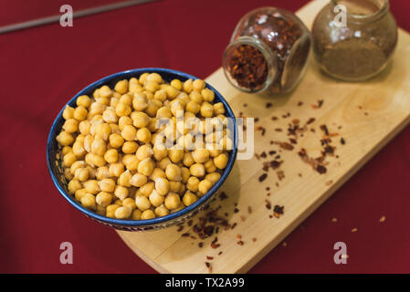 Vorbereitung für das Kochen von Kichererbsen und pilaw. Gelbe Kichererbsen liegen in einem orientalischen Platte auf einer hölzernen Spice board Stockfoto