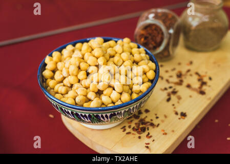 Vorbereitung für das Kochen von Kichererbsen und pilaw. Gelbe Kichererbsen liegen in einem orientalischen Platte auf einer hölzernen Spice board Stockfoto