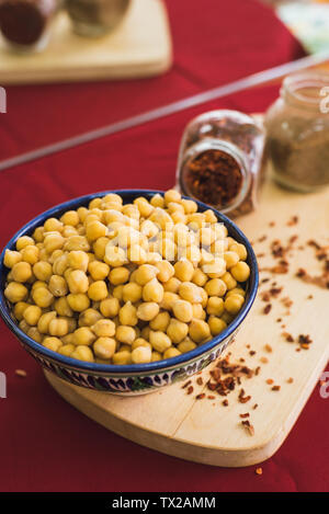 Vorbereitung für das Kochen von Kichererbsen und pilaw. Gelbe Kichererbsen liegen in einem orientalischen Platte auf einer hölzernen Spice board Stockfoto