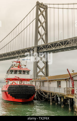 San Francisco Feuerlöschboot günstig mit der Bay Bridge im Hintergrund. Stockfoto