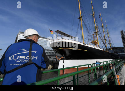 Wewelsfleth, Deutschland. 24. Juni, 2019. Das Segelschiff "Peking" liegt vor dem Trennen von einer Erweiterungsstation herunter, in der Werft, ein Arbeiter am Pier steht. Die traditionelle Sailor 'Peking' soll sich auf seine eigene Kiel wieder zu schwimmen nach einer längeren Liegezeit. Die Arbeiten sollen im Mai 2020 abgeschlossen sein. Die 'Peking' wird später seinen letzten Liegeplatz in der geplanten deutschen Hafen Museum im Hamburger Hafen haben. Credit: Carsten Rehder/dpa/Alamy leben Nachrichten Stockfoto