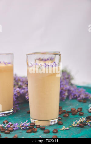Sommer trinken Eiskaffee mit Lavendel in Glas und Kaffeebohnen auf grünem Hintergrund. Guten Morgen Konzept. Baeutiful Eis Kaffee. Stockfoto