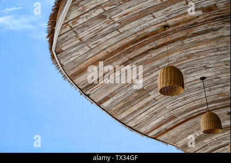 Holz- Strohdach mit Lampe aufhängen und blauer Himmel Stockfoto