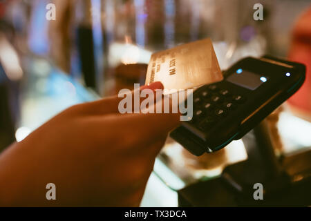 Hände von Barista mit einem Payment Terminal im Coffee Shop. 7/8-schuss. Barista im Besitz einer Kreditkarte über einen Reader Maschine nach Zahlungen. Stockfoto
