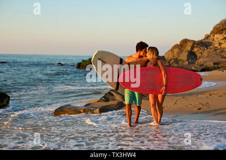 Junge, zärtlich Paar mit Surfbrettern auf sonnigen Ocean Beach, Sayulita, Nayarit, Mexiko Stockfoto