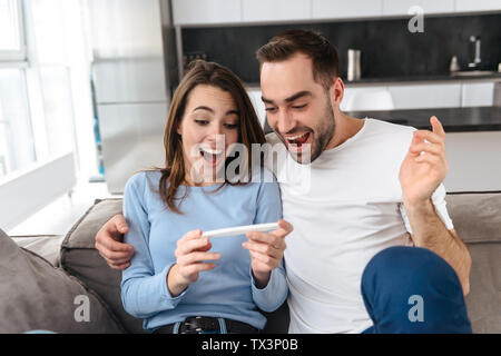 Reizende junge Paar holdingpregnancy Test, Feiern Stockfoto