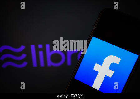 In diesem Foto, Bild a facebook logo gesehen auf einem Smartphone mit Libra Logo angezeigt, die Facebook crypto Währung Logo im Hintergrund. Stockfoto