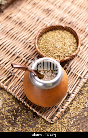 Yerba Mate und Tee mate in der kalebasse auf einem Korb Tablett auf einem hölzernen Hintergrund Stockfoto