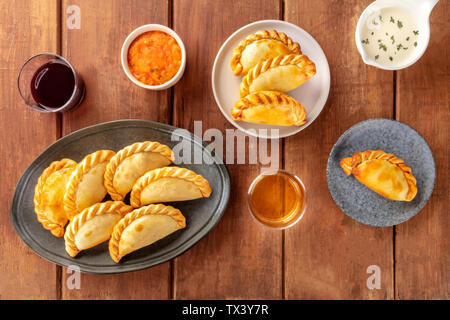 Empanadas mit Saucen und Wein, Schuß von der Oberseite in einem dunklen Holzmöbeln im Landhausstil Hintergrund Stockfoto