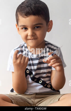 Ein wenig schlechter Junge Sie die Spritze und den Aufruf jemand mit seinem Finger. Ein Kind Spaß am Krankenhaus. Stockfoto