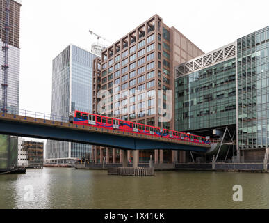 Canary Wharf, London, Großbritannien: Ein Zug der Docklands Light Railway kommt vom Bahnhof Heron Quays, um eine Brücke über South Dock zu überqueren. Stockfoto