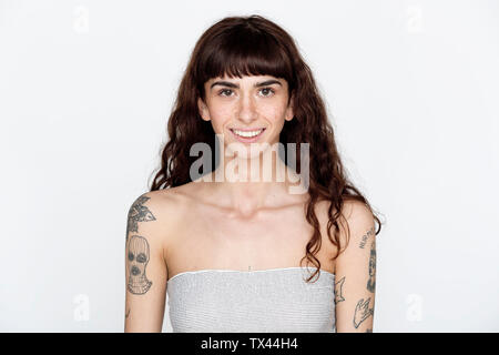 Portrait von lächelnden jungen Frau mit Sommersprossen und Tattoos auf ihre Oberarme Stockfoto