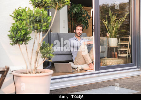 Junge Mann in seinem gemütlichen zu Hause, schaut aus dem Fenster Stockfoto
